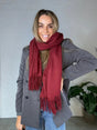 Kvinde iført Andcopenhagen Basics 70% cashmere tørklæde i bordeaux, stylet over grå frakke.