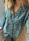Grøn pyjamas med pink og blå blomster, knapper på toppen, løse bukser, bæres af en person.