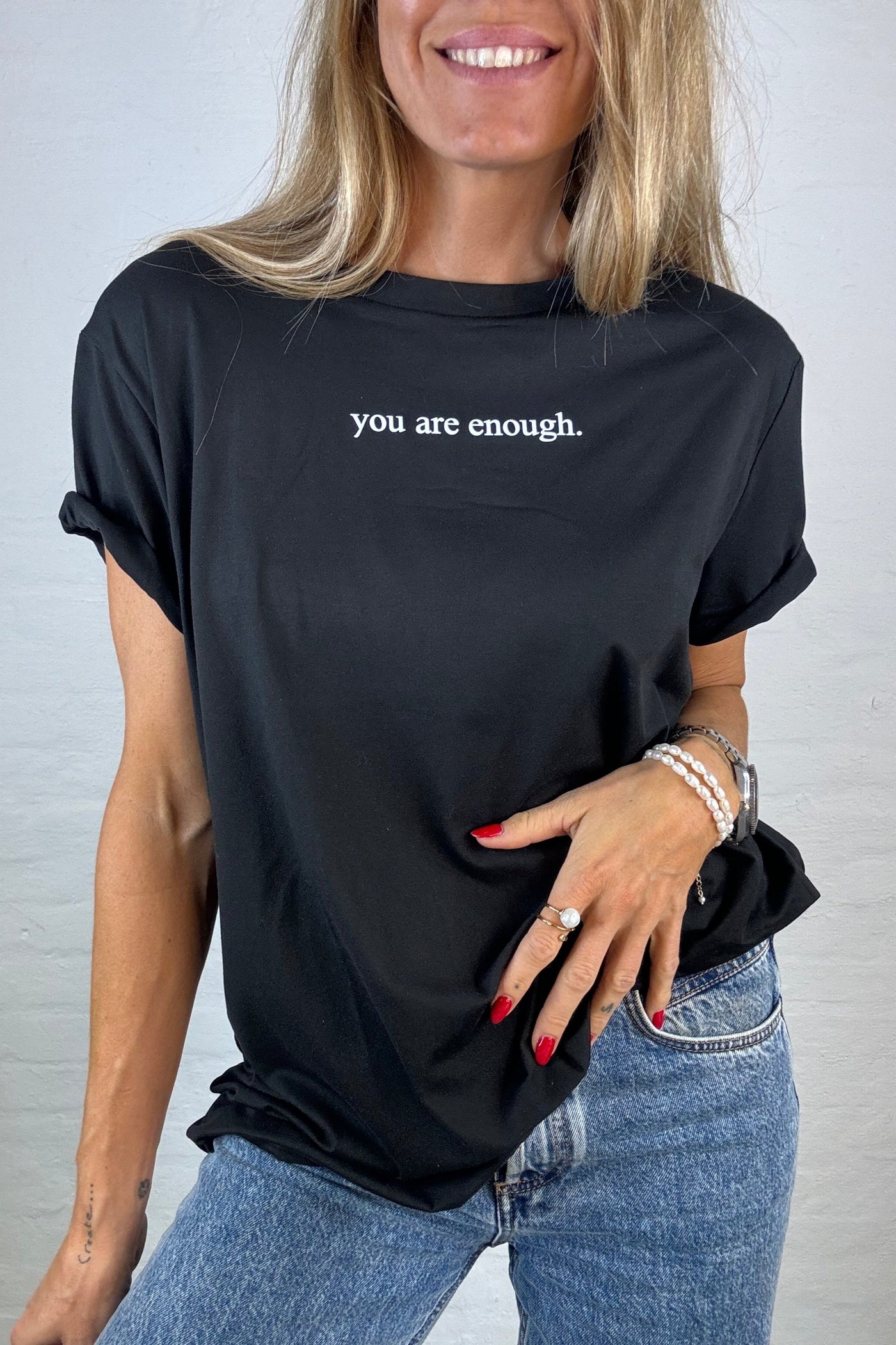 Sort T-shirt med teksten "you are enough", bæres med jeans.