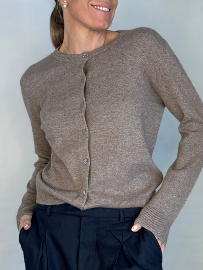 Kvinde iført mørk kaffefarvet cashmere cardigan med knapper, kombineret med mørke bukser.