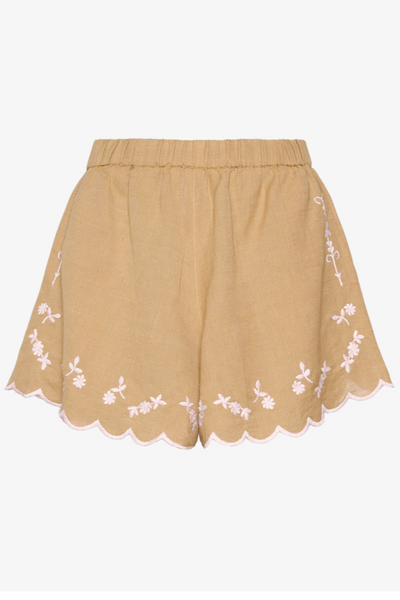 Lysebrune shorts med elastisk talje, bølgede kanter og hvid blomsterbroderi langs sømmen.