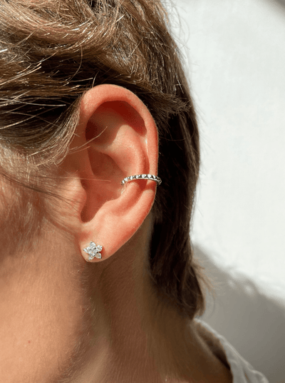 Øre med to øreringe; en blomst med glitrende sten og en enkel, mønstret hoop.